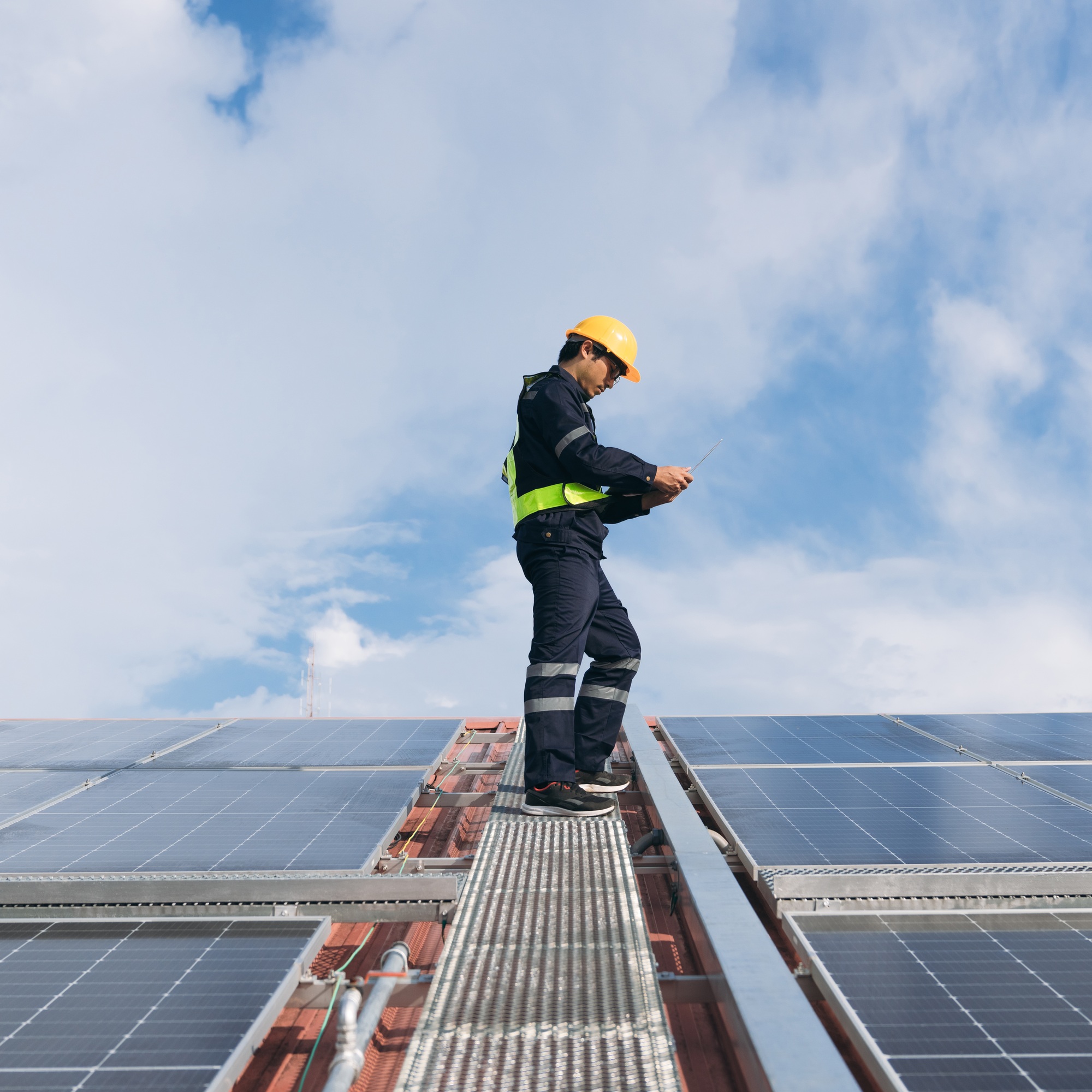 Service engineer checking solar cell on the roof for maintenance if there is a damaged part.